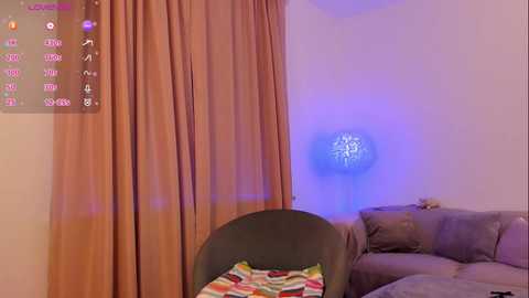 Video of a cozy living room with a dark green armchair, striped pillow, beige curtains, and a glowing blue orb on the wall.