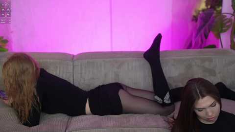 Media: Video of two young women in black clothes, one lying on a sofa with legs in the air, the other sitting, both wearing black stockings.