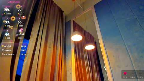 A video of a dimly lit room with brown, floor-length curtains and two hanging, spherical, golden light fixtures. The background features a large, mirrored wall, and a digital display shows various icons and information.