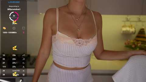 Video of a slender Caucasian woman in a white, lace-trimmed bra and matching skirt, standing in a modern kitchen with yellow walls.