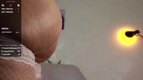 Video of a woman's large, bare buttocks and thigh, in lace panties, with a blurred background featuring a yellow light bulb.