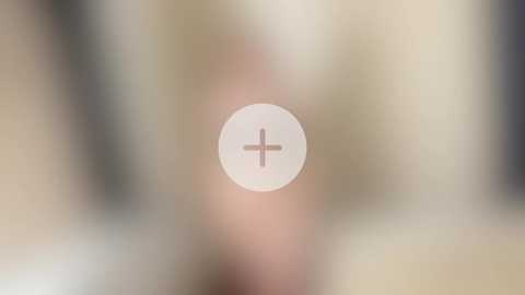 A blurry video with a central focus on a circular object with a cross symbol, surrounded by indistinct, out-of-focus figures and a beige, light-colored background.