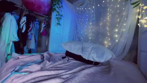 A video of a dimly lit, whimsical bedroom with a white canopy bed, fairy lights, and clothes hanging in a closet, bathed in blue and pink hues.