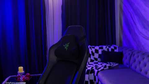 Video of a black gaming chair with a green logo on a black-and-white checkered couch in a dimly lit room with blue and purple lighting.