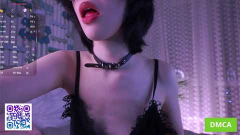 Video of a fair-skinned woman with short black hair, wearing a black lace bralette and a black choker, mouth slightly open, against a purple-lit, dimly-lit background with a \"DMCA\" watermark.