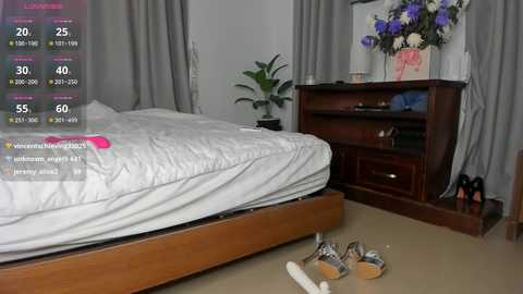 A video of a messy bedroom with a wooden bed, gray curtains, a dresser with a bouquet, and scattered shoes and clothes.