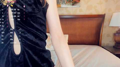 A video of a woman in a black dress, leaning against a wooden headboard in a beige-tiled bedroom. A digital calendar and clock overlay the image, indicating the date and time.