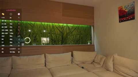 Video of a modern living room with a large aquarium as a room divider, displaying a lush green forest scene, and a beige sectional sofa with cushions.