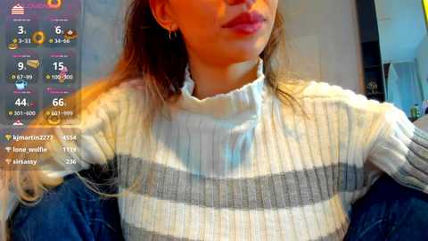 Video of a woman with light skin, wearing a white and gray striped sweater, indoors, with social media app icons overlaid.