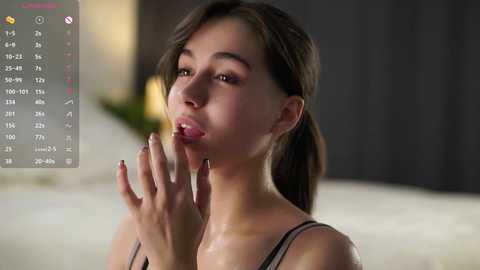 Media: Video of a young woman with olive skin, brown hair, and dark eyes, holding a lit cigarette. She's wearing a black top, indoors with blurred background.