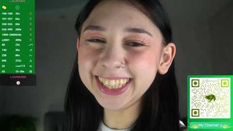 Video of a young woman with long black hair, light skin, and a small nose piercing, smiling widely, background blurred, green screen overlay with \"MyChameleon\" logo and QR code.