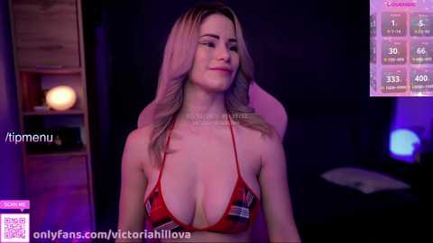 A video of a young, fair-skinned woman with long, wavy blonde hair, wearing a red bikini top, seated indoors with purple lighting, displaying a watermark \"immenu\" and OnlyFans link.