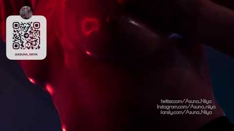 A video showcasing a red-lit, semi-nude person with a tattoo, blurred in the foreground. The image includes a QR code and social media handles.