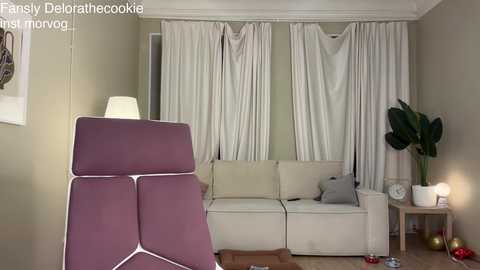 A video of a living room with beige walls, white curtains, a cream sofa, a purple armchair, a green plant, a white lamp, and a clock.