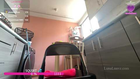 A video captures a cluttered kitchen with a black chair, pink toy, and a messy countertop, featuring beige walls, cabinets, and a water dispenser.