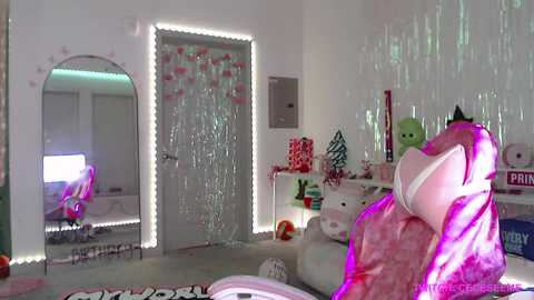 Video of a girly, light-pink bedroom with a unicorn plush, pink fairy lights, white walls, and a glittery door, featuring a mirror, plush toys, and festive decorations.