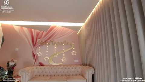 Video of a luxurious, pink-themed interior with a tufted beige couch, gold \"Welcome\" sign, and beige drapes, set against a backdrop of abstract, flowing pink and white patterns.