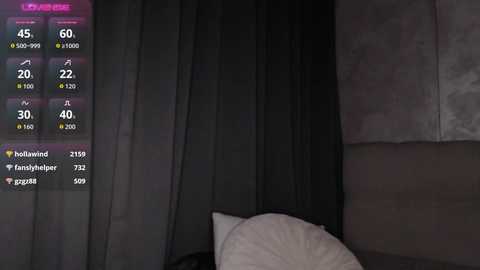 A video shows a dimly lit room with a grey curtain, a white pillow, and a digital display showing a weather forecast. The room has a modern, minimalist aesthetic.