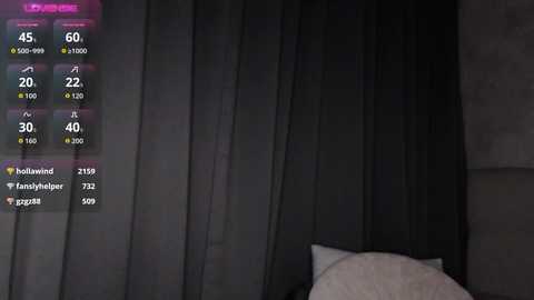 A video of a dimly lit bedroom with dark curtains, a white pillow, and a digital display showing wind speed, temperature, and location data.