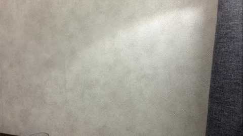 Video of a textured, light beige wall with subtle diagonal lines and a dark gray fabric texture on the right side. The image captures a minimalistic, modern interior design style.