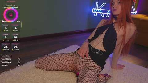 Video of a pale-skinned, long-haired woman in black fishnet lingerie, sitting on a plush white rug, in a dimly lit room with neon lights.
