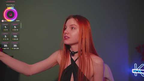 Video of a pale-skinned, red-haired woman in a black halter top, gesturing with her left hand. Background shows a digital clock and a \"KTLA\" logo.