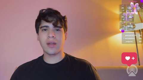Video of a young man with curly hair, wearing a black t-shirt, against a warm-toned background with social media icons overlaying his image.