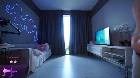 A video of a modern, dimly lit living room with a neon blue wave wall mural, white sofa, and a flat-screen TV on a white cabinet.