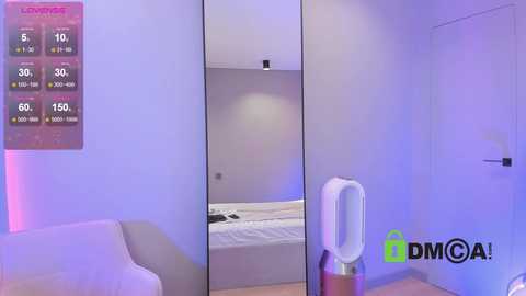 Video of a minimalist, well-lit bedroom with a large mirror, white bed, and purple accent lighting. A digital thermostat and a DMMGA logo are visible.