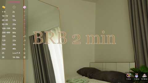 Video of a minimalist bedroom with a full-length mirror, a bed with grey pillows, and a wall-mounted clock displaying \"BBB 2 min\" in a muted color scheme.