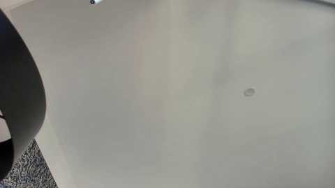 Media: Video of a gray car's windshield, showing a small, round, circular scratch near the center. The background features a dark, textured surface.