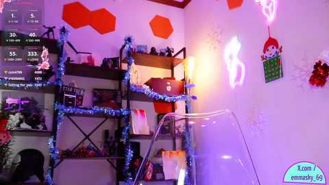 A video of a room decorated with festive Halloween elements, including a ghost, orange lights, and a clear chair. The background features a shelf with various items and a TV displaying a game.