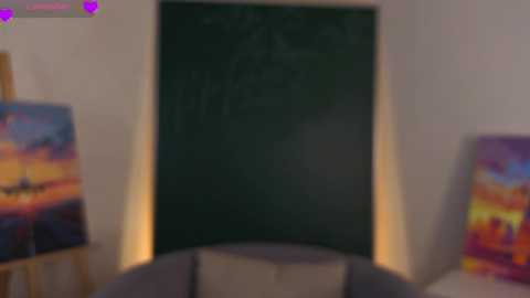 A blurred video of a dark wall with a vibrant, colorful painting above it. The background features a sofa with cushions. The image is slightly out of focus.