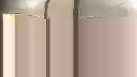 Video of a minimalist, beige-painted wall with a vertical, metallic, vertical support structure. The image is well-lit with a soft, diffused light creating a serene and clean aesthetic.