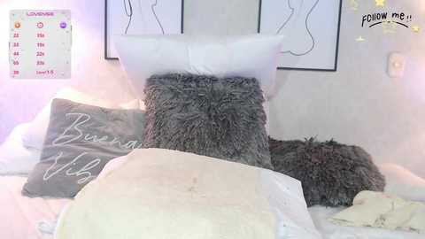 Video of a cozy, minimalist bedroom featuring a fluffy gray throw, white pillows, and a calendar. Soft pastel lighting and minimalist art on the wall create a serene atmosphere.