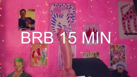 A video featuring a large, erect penis on a black table in a brightly lit, pink-walled room adorned with posters. Text reads \"BBR 15 MIN.\