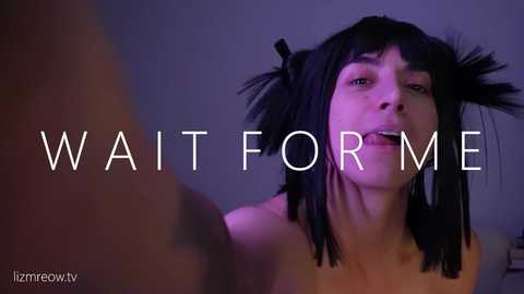 A video of a topless woman with straight black hair in pigtails, looking upward with a seductive expression. Text on the image reads \"WAIT FOR ME.\