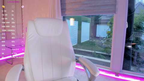 A video of a modern, minimalist room featuring a white leather recliner chair with neon pink lights underfoot, facing a large window with a view of a garden and a lake.