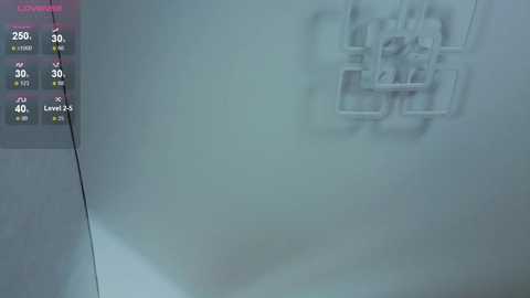 A video of a dimly lit, white-walled room showing a metal contraption hanging from the ceiling, resembling a cross between a spider and a birdcage. A digital display on the left side shows temperature, humidity, and air quality readings.