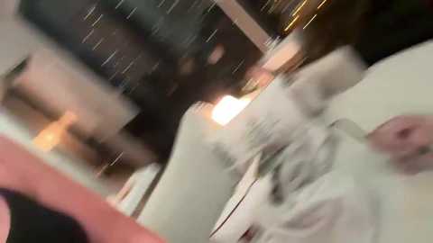A blurry video of a white man, possibly middle-aged, with long, wavy hair, wearing a white shirt, seen from the side, possibly in a bar or dimly lit indoor setting.