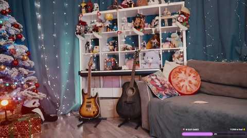 A cozy, festive living room with a snow-covered Christmas tree, white bookshelf adorned with ornaments, guitar, and a plush cat, alongside a grey sofa with a large orange slice pillow.