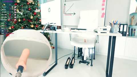 Media: A video of a modern office with a white desk, white chair, and a Christmas tree in the background; a prosthetic hand is visible in the foreground.