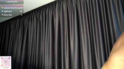 A video of a room with a black, pleated velvet curtain covering the window, showing the ceiling and a blurred, partially visible person in the foreground.
