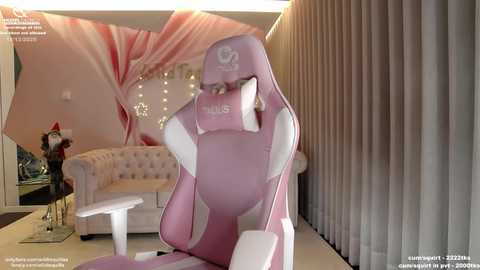 Video of a pink gaming chair in a chic, modern living room with beige curtains, a white couch, and a Christmas tree in the background.