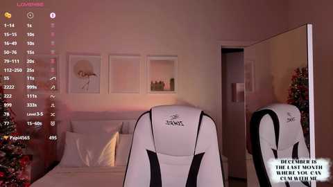 Video of a modern bedroom with a white chair facing a white bed. Framed art pieces adorn the wall, and a Christmas tree decorates the left side. Text on the right reads, \"December is the last month when you can win a car.\