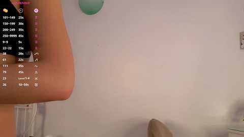 A screenshot from a virtual reality game showing a close-up of a person's right arm and hand, with a table and blue objects in the background.