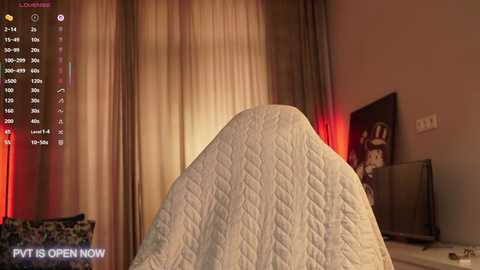 Video of a cozy bedroom with a white quilted blanket on a bed, soft beige curtains, a flat-screen TV, and a \"PIT IS OPEN NOW\" message on a phone screen.