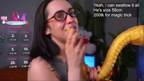 A video of a tattooed woman with glasses, smiling while holding a yellow banana, surrounded by digital stats and text.