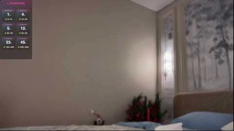 Video of a beige-walled bedroom with a bed, a temperature gauge, and a floral painting; the room has a serene, minimalistic feel.