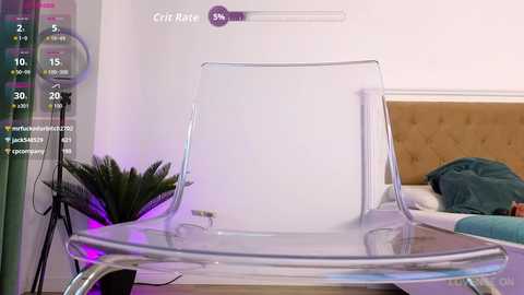 Media: Video of a modern, minimalist bedroom with a clear acrylic chair and a green plant on a wooden table against a white wall.